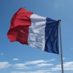 A clear blue sky with the French flag waving vibrantly, symbolizing patriotism and freedom.